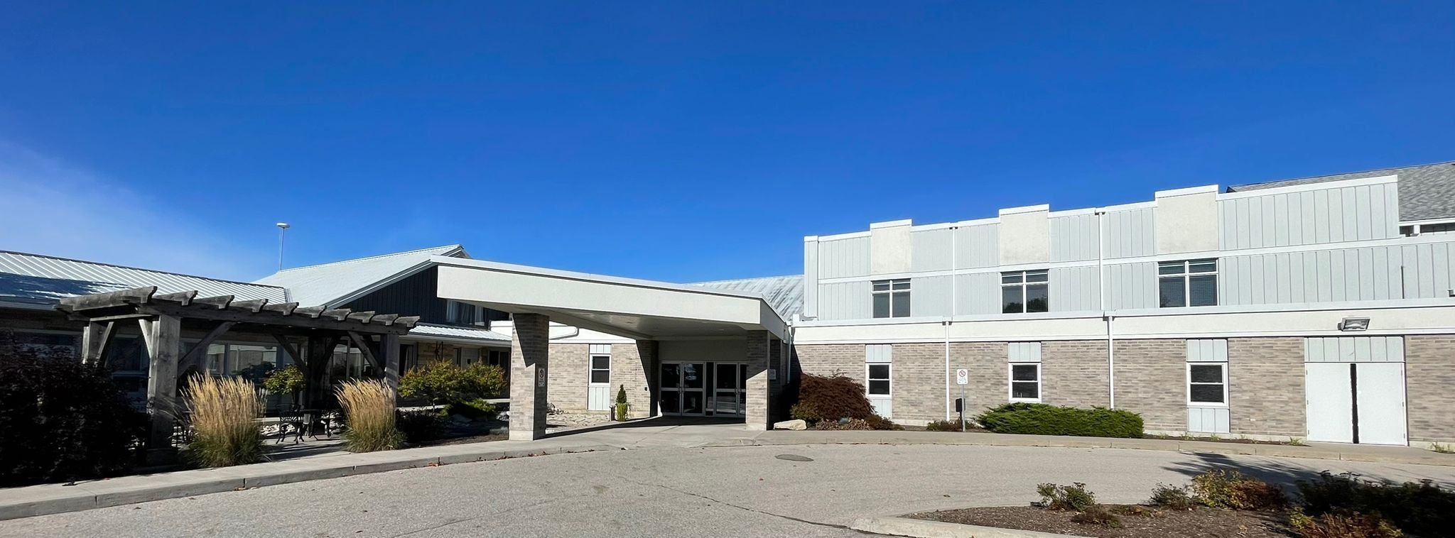 The covered front entrance of Elora Road Christian Fellowship, a long brick and grey-sided building with a pergola