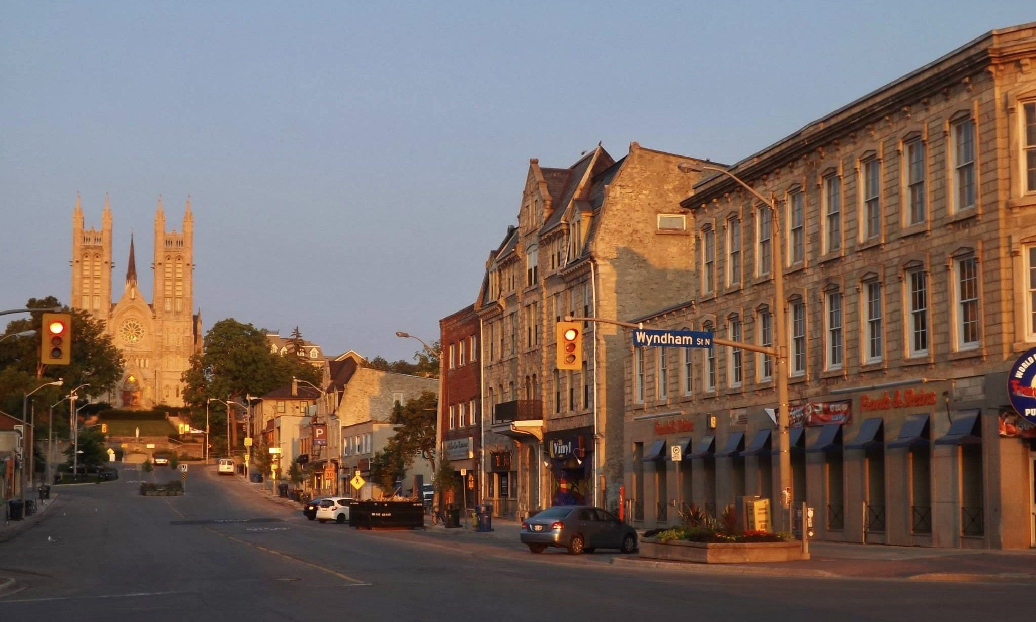 Limestone buildings along Macdonell Street in morning light, with the twin towers of the Basilica of Our Lady Immaculate at the end of the street
