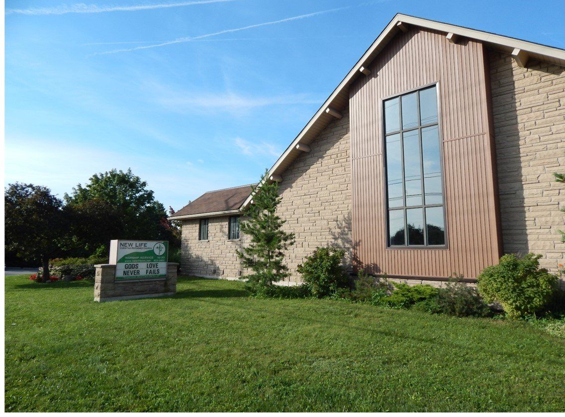 New Life Christian Reformed Church, a stone and wood building with a tall window, beside its sign